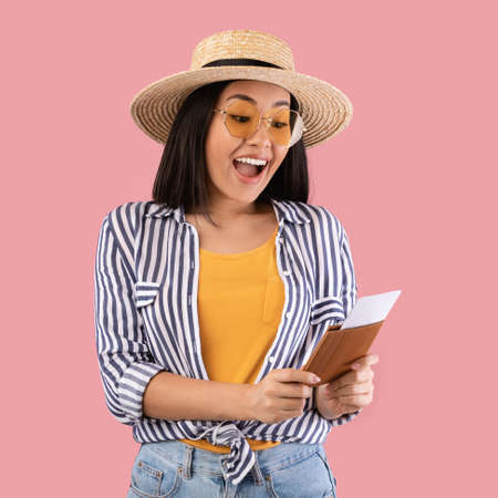 Asian woman holding and looking at passport with ticketsの写真素材