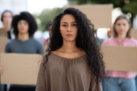 Confident young woman over group of activists