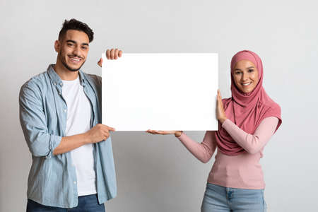 Cheerful Middle Eastern Couple Holding Blank White Placard With Copy Spaceの写真素材