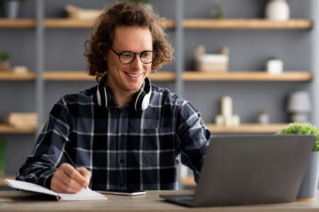 Young Businessman At Laptop Taking Notes Working In Modern Office