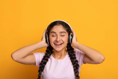 Positive Young Indian Woman Listening To Music Wearing Headsetの写真素材