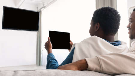 Black couple watching TV and using digital tabletの写真素材