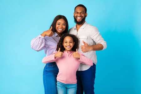 Happy black family gesturing thumbs up and smilingの写真素材