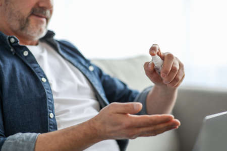 Cropped of senior man with laptop disinfecting handsの写真素材