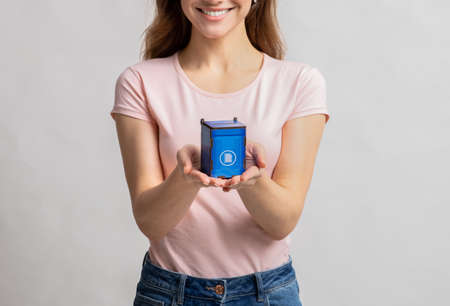 Smiling Young Female Holding Small Blue Toy Recycle Bin For Paper Waste