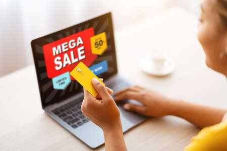 Black woman using laptop and credit card at homeの写真素材