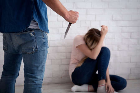 Victim afraid of tyrant, frightened lady covers her face with hands and sits on floor
