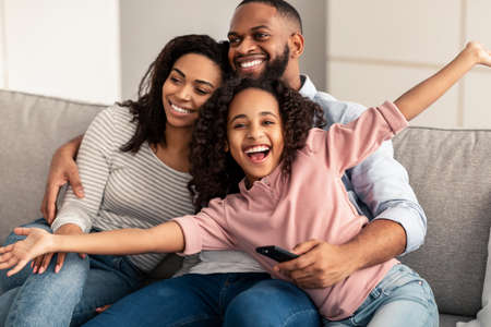 Happy young family watching television sitting on sofaの写真素材