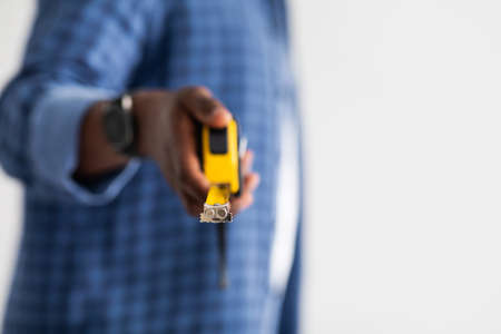 African american handyman holding measuring tape, isolated on white background with copy space,...