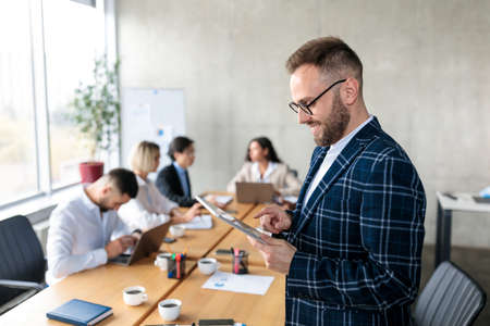Smiling Businessman Using Digital Tablet Standing In Officeの写真素材