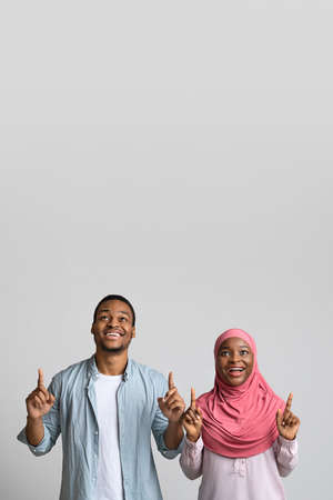 Black man and woman pointing up at empty space