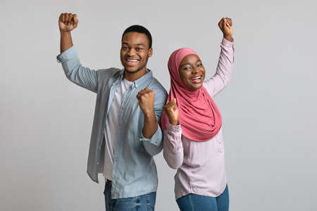 Emotional african american couple celebrating success, clenching fists and dancingの写真素材