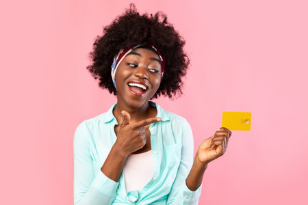 Cheerful Black Woman Pointing Finger At Credit Card In Studioの写真素材