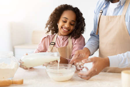 Happy black family preparing dough together in kitchenの写真素材