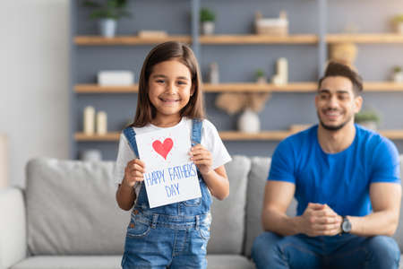 Little daughter greeting young dad with card