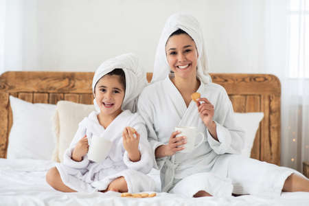 Cheerful mummy and kid drinking tea, eating cookiesの写真素材
