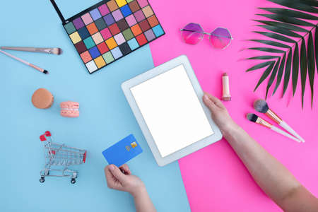 Cosmetics and online shopping concept. Female hands using digital tablet with blank screen and holding credit cardの写真素材