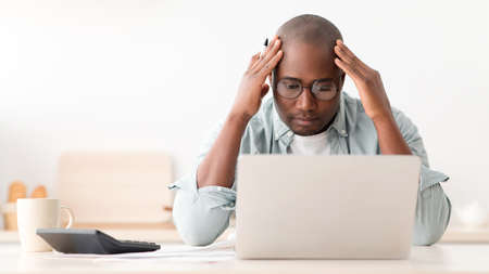 Financial crisis concept. Upset black middle-aged man checking bills, managing household budget,...