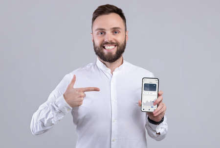 Happy businessman holding phone with financial app on screen