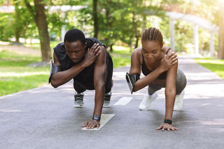 Black Athlete Couple Making One Hand Plank Exercise Together, Training Outdoorsの写真素材