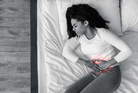 Black woman suffering from stomachache, touching her tummyの写真素材