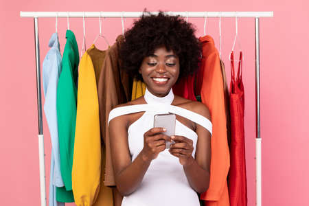 Happy Black Female With Smartphone Buying Clothes Online, Studio Shot