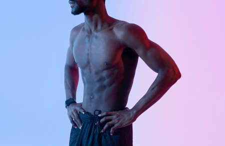 Closeup view of sexy young black guy with muscular bare torso posing in neon light. Strength workout conceptの写真素材