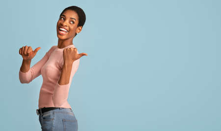 Check This. Cheerful African American Female Pointing Back With Two Thumbs Up