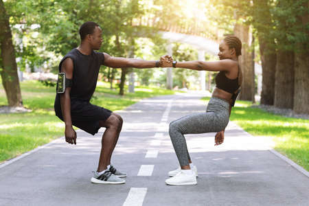 Teamwork In Sport. Active Black Couple Exercising Together In City Park