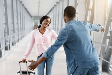 Happy African American Woman Meeting With Boyfriend In Airport Terminal After Arrivalの写真素材