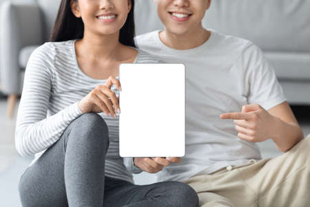 Closeup of asian couple holding digital tablet with blank screenの写真素材