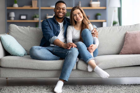 Portrait Of Happy Young Interracial Spouses Posing On Couch At Homeの写真素材