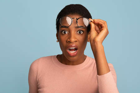 Confused Black Female Taking Off Glasses And Looking At Camera With Shockの写真素材