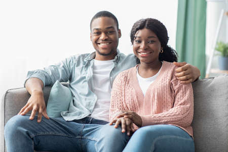Loving black couple sitting on sofa in living roomの写真素材