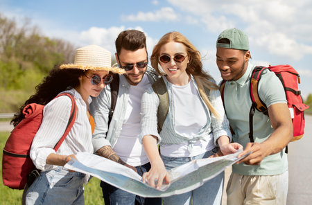 Local travel. Group of young people studying map on roadside, checking their destination point,...