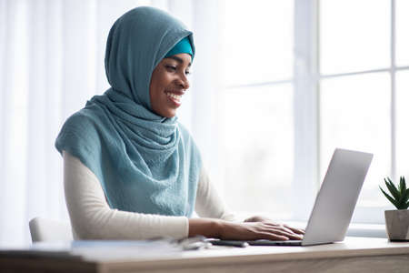 Remote Work. Happy Black Muslim Freelancer Lady In Headscarf Using Laptop Computer