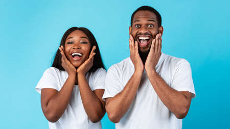 Portrait of excited young black couple hearing great newsの写真素材