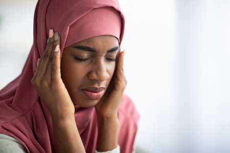 Migraine Concept. Black Islamic Lady In Hijab Suffering From Headache At Homeの写真素材