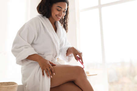 Pretty African Young Woman Making Depilation Shaving Legs In Bathroom