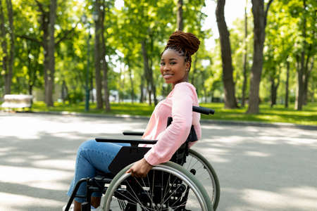 Positive handicapped black lady in wheelchair enjoying wonderful summer morning outdoorsの写真素材