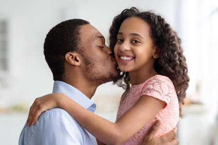 Handsome black father kissing his cute little daughterの写真素材
