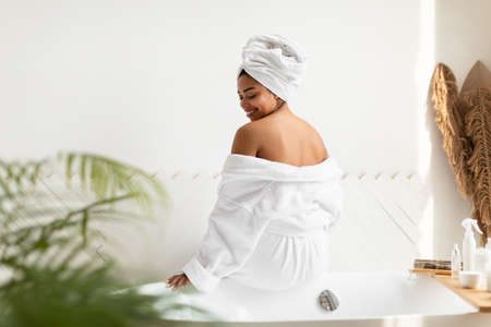 Black Woman Sitting Back To Camera Preparing Bath At Homeの写真素材