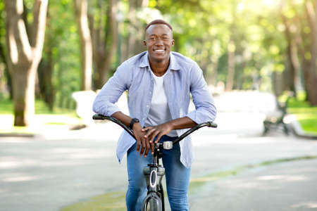 Urban adventure concept. Happy guy on a fun bicycle ride at the city parkの写真素材