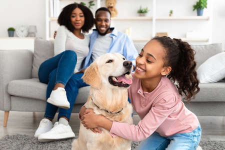 Young black girl hugging dog posing at homeの写真素材