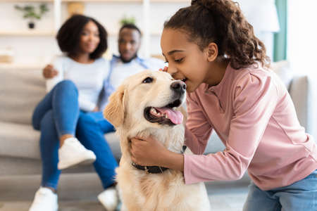 Young black girl hugging with dog and whispering secret