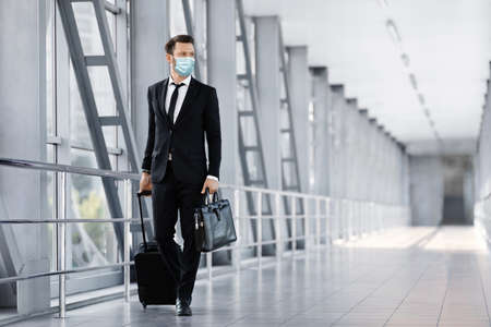 Businessman in face mask walking by airport terminalの写真素材