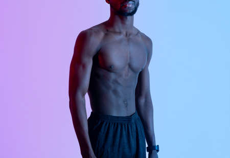 Cropped view of handsome young black sportsman with naked torso posing in neon lightの写真素材