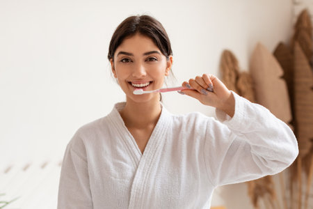 Woman Brushing Teeth With Toothbrush Smiling Standing In Bathroom Indoorの写真素材