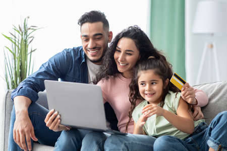 Middle Eastern Family Of Three With Laptop And Credit Card At Homeの写真素材