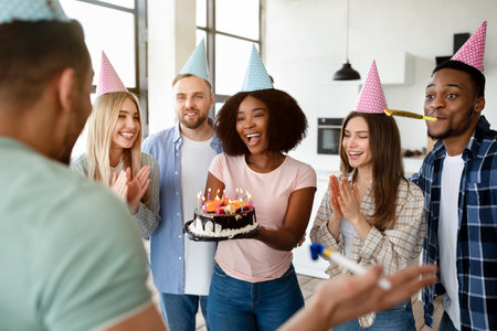 Group of happy diverse friends having birthday celebration, congratulating their fellow student,...